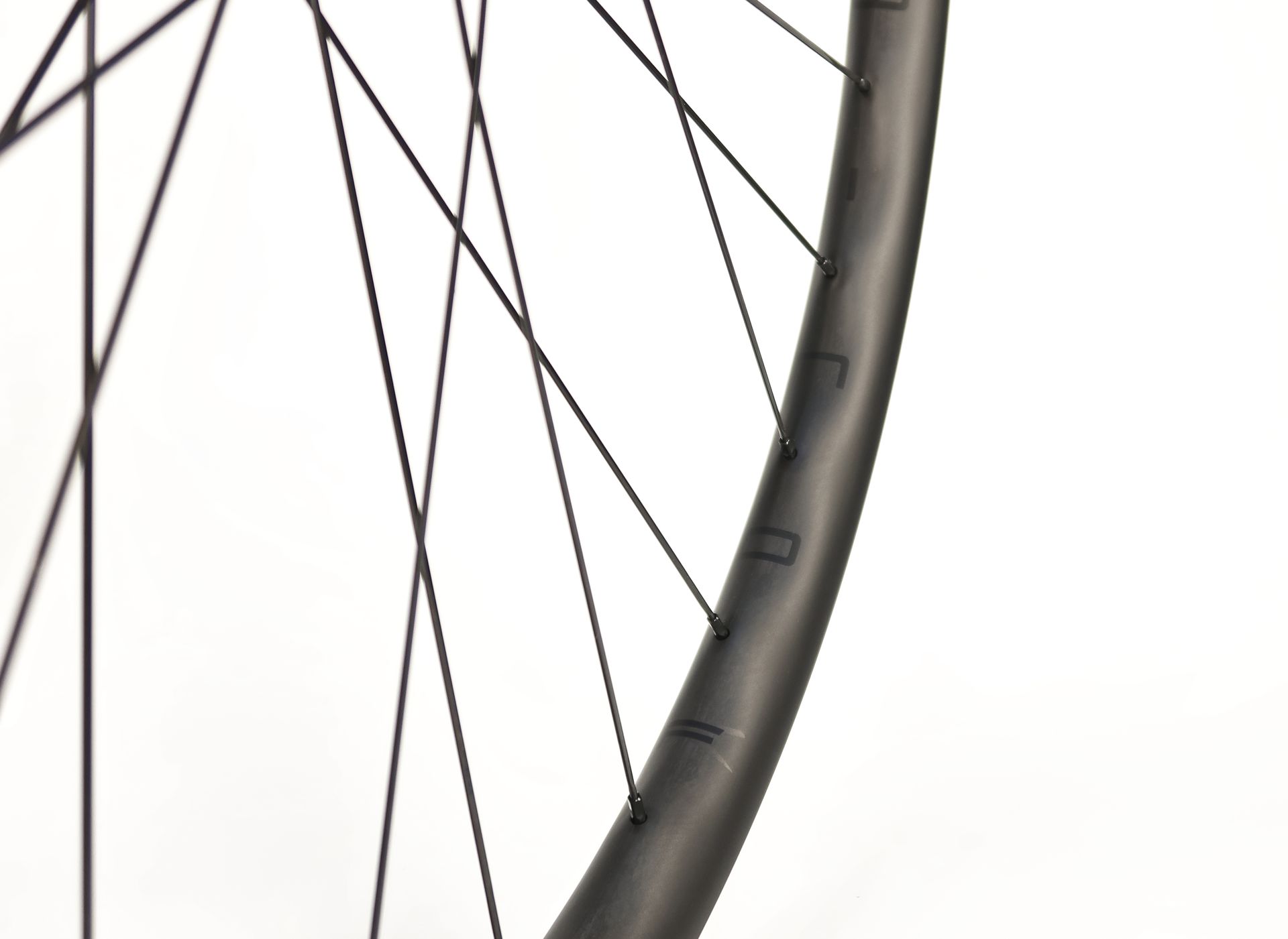 A close up of a wide waved carbon bicycle wheel on a white background