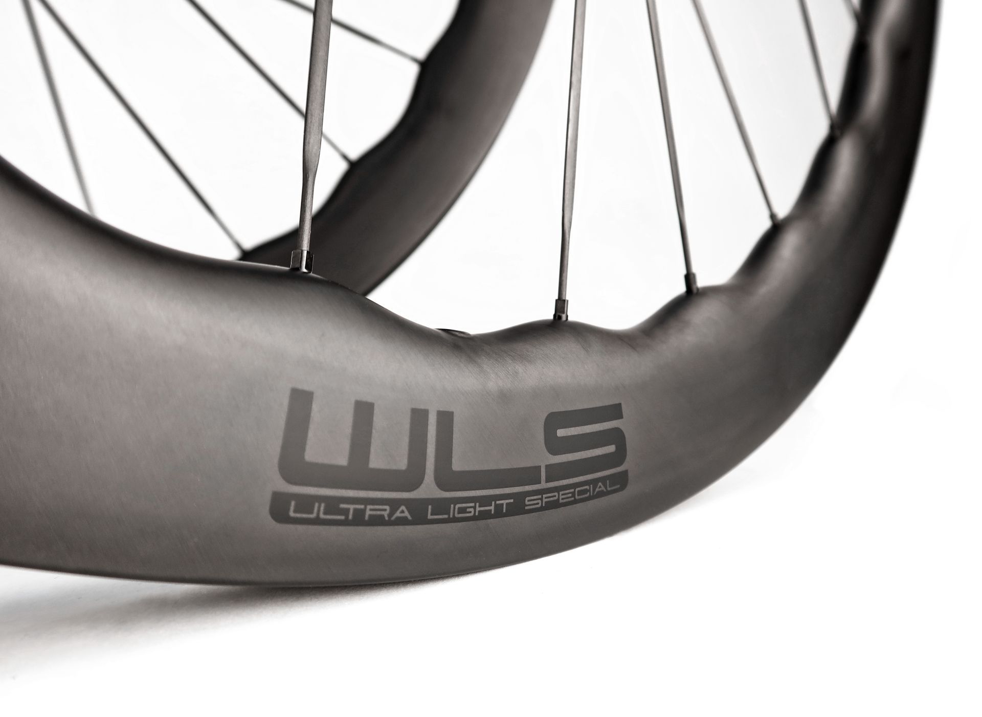A close up of a waved carbon aero wls ultra light bicycle wheel with carbon spokes