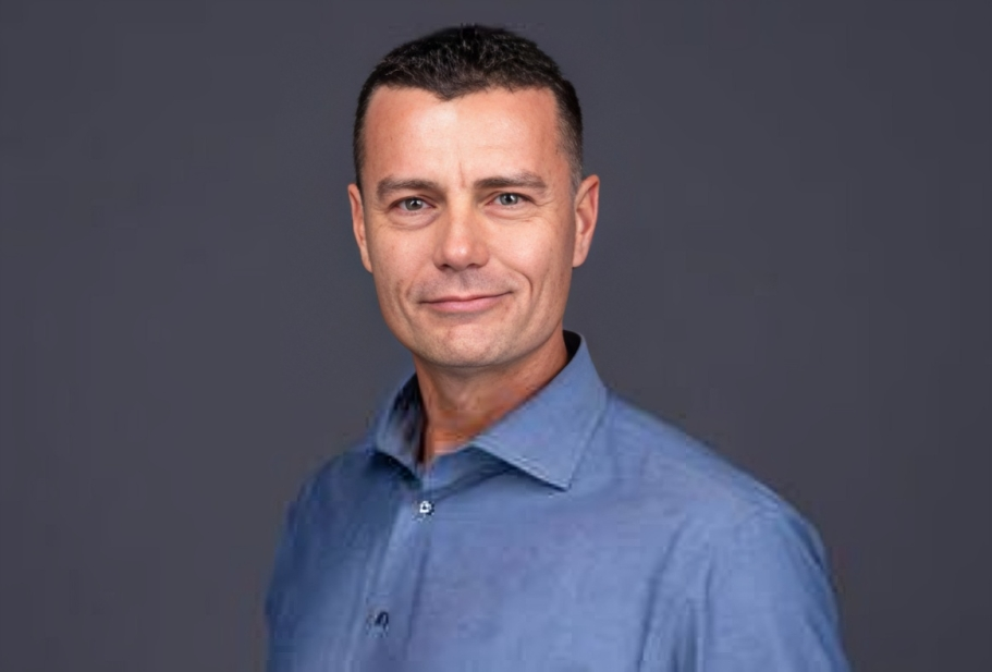 Portrait of a man in a blue shirt against a gray background