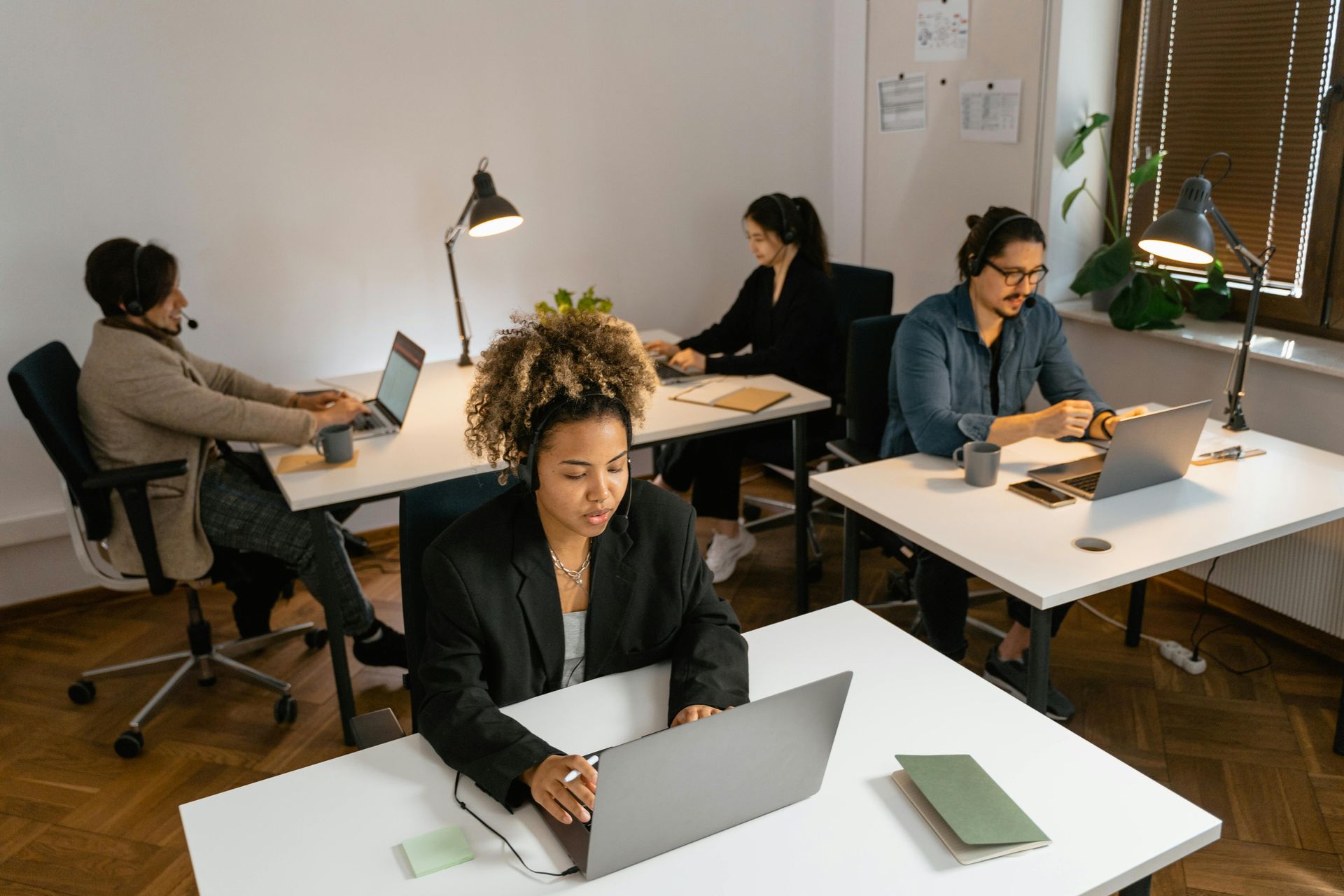People working on laptops at desks in a bright modern office