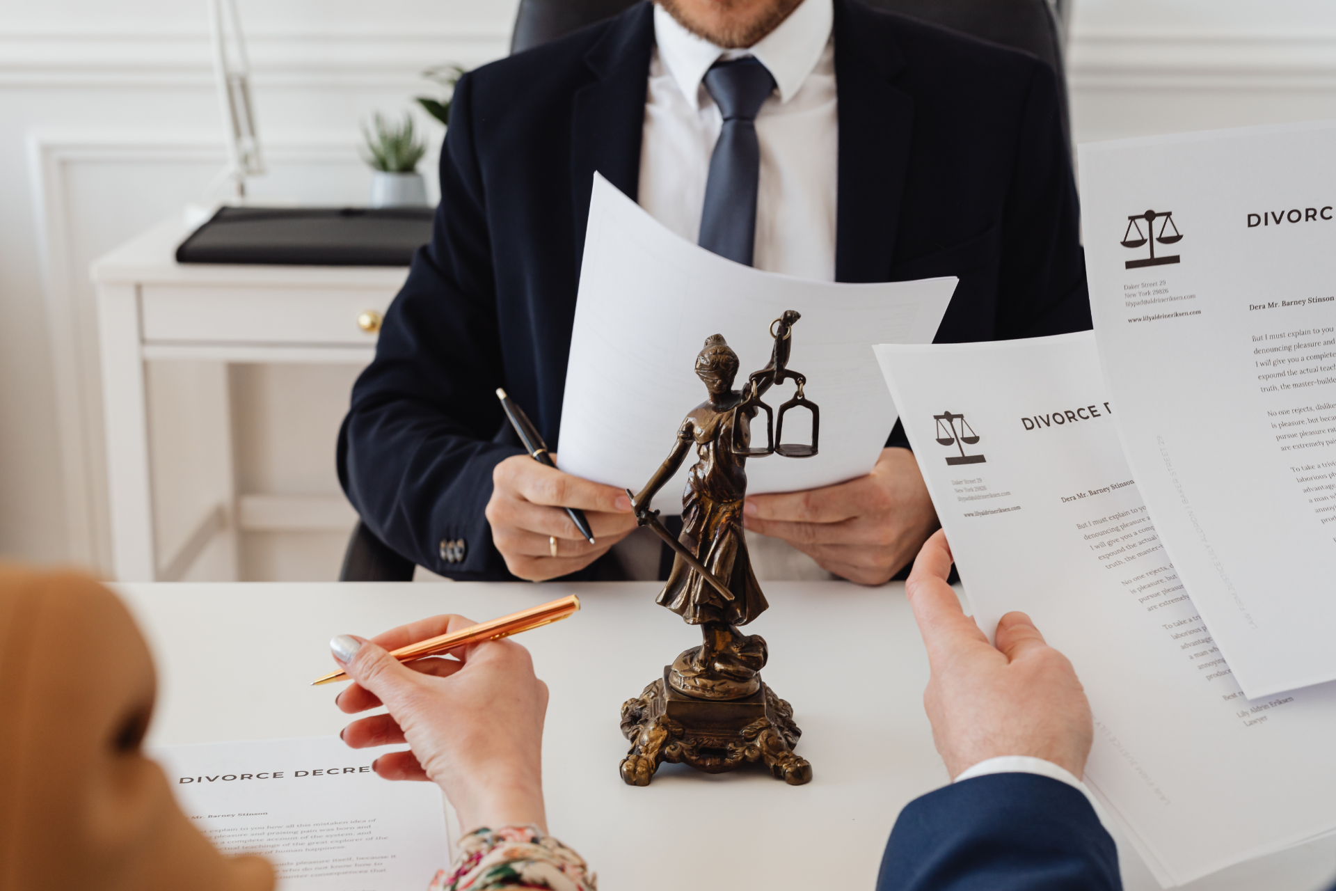 Business meeting with legal documents, a judge statue, and hands reviewing papers at a desk