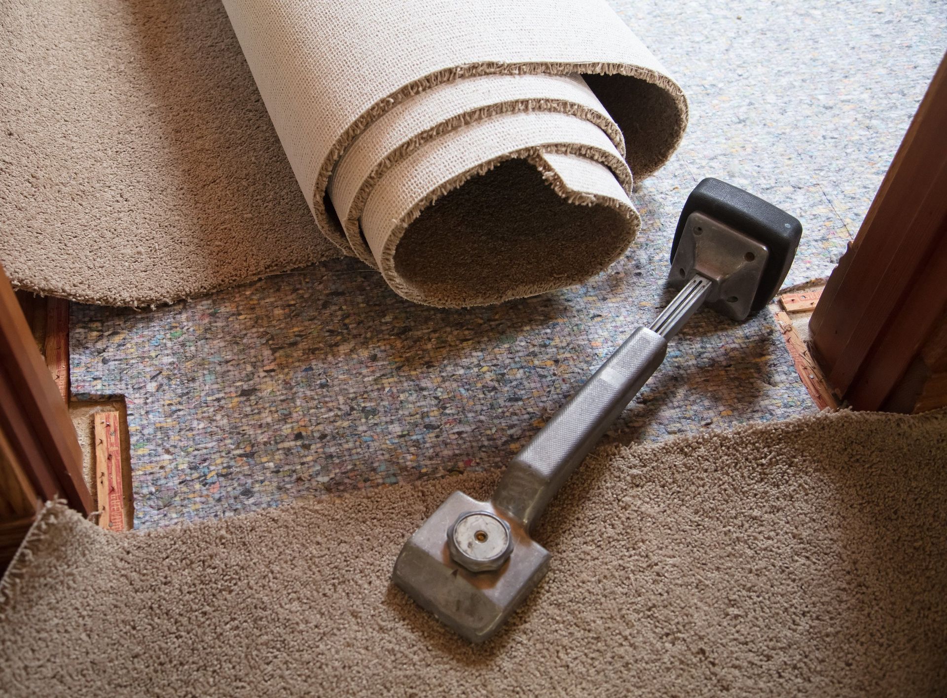 A roll of carpet is sitting on top of a staircase next to a door.