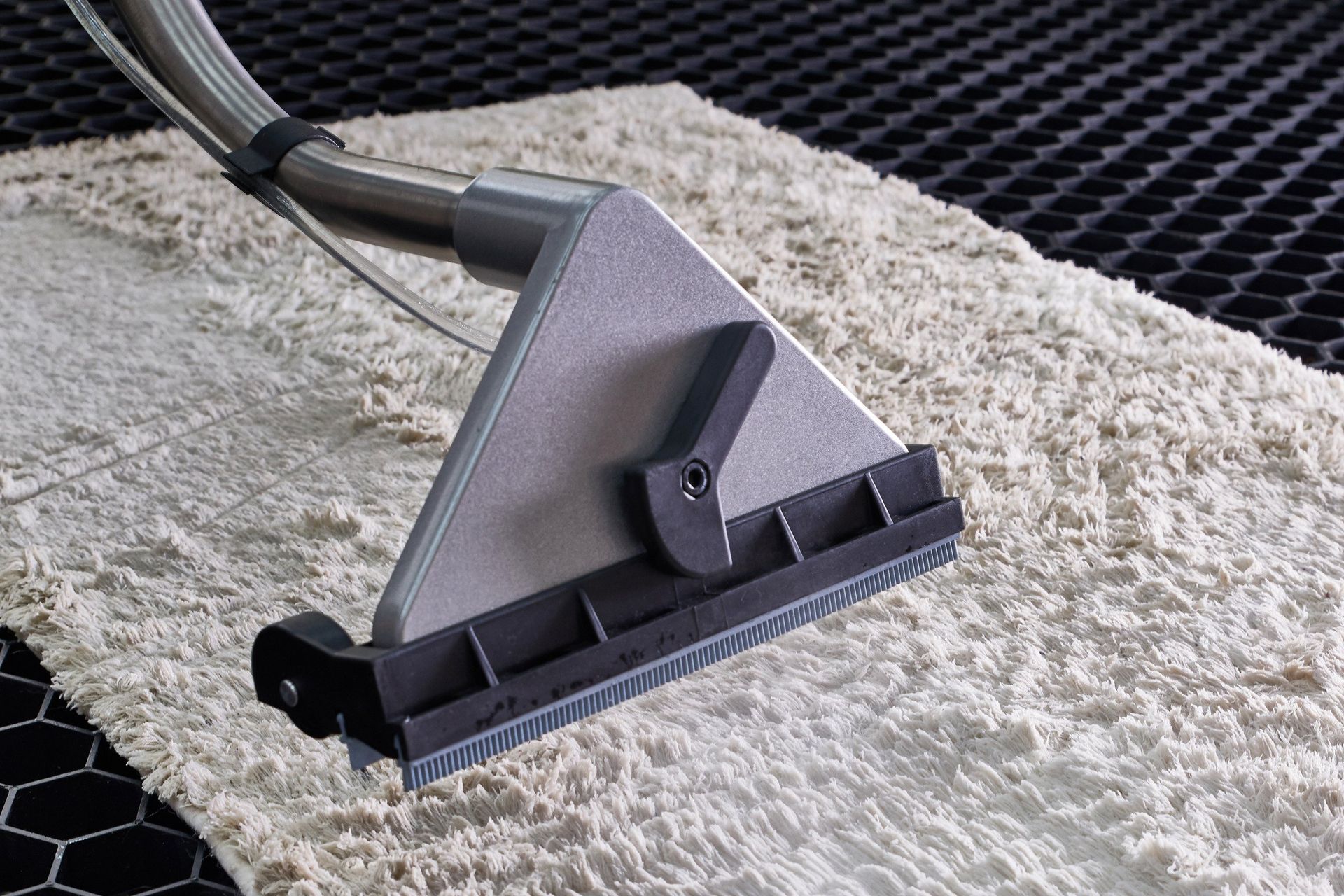 A vacuum cleaner is cleaning a carpet with a brush.