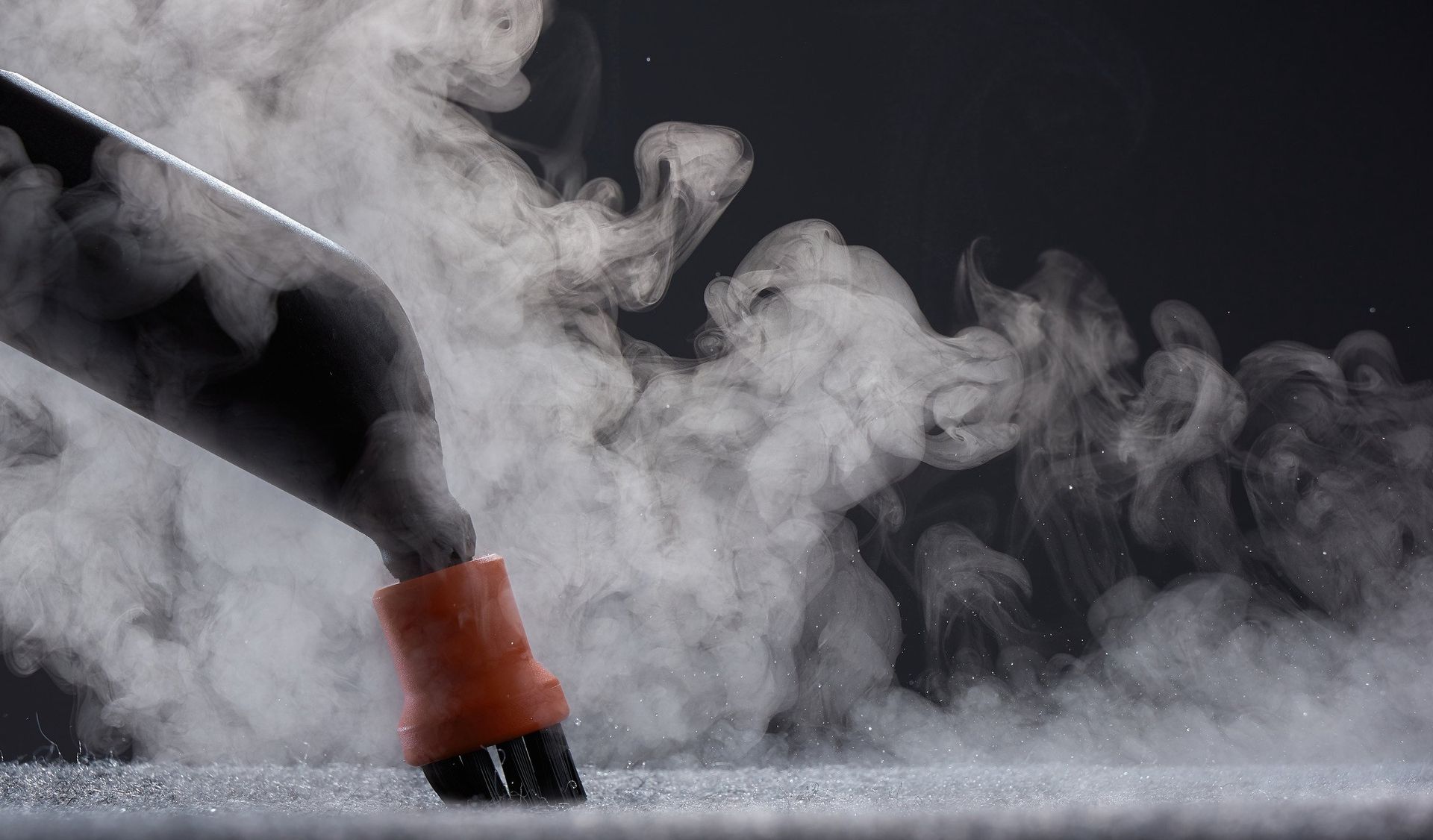 A person is using a steam cleaner to clean a carpet.