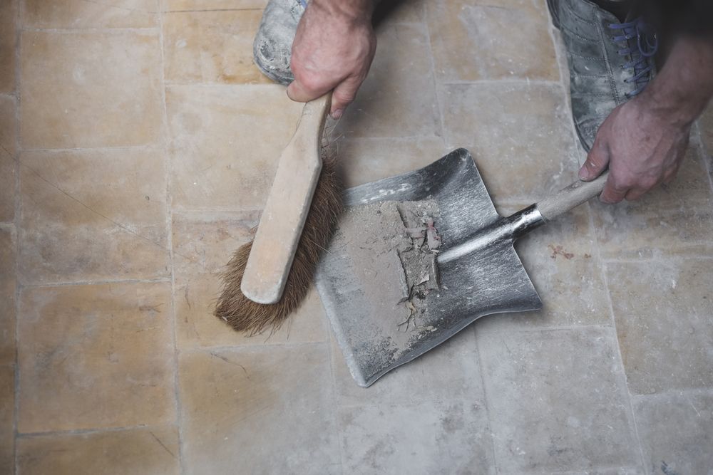 A person is cleaning the floor with a broom and shovel.