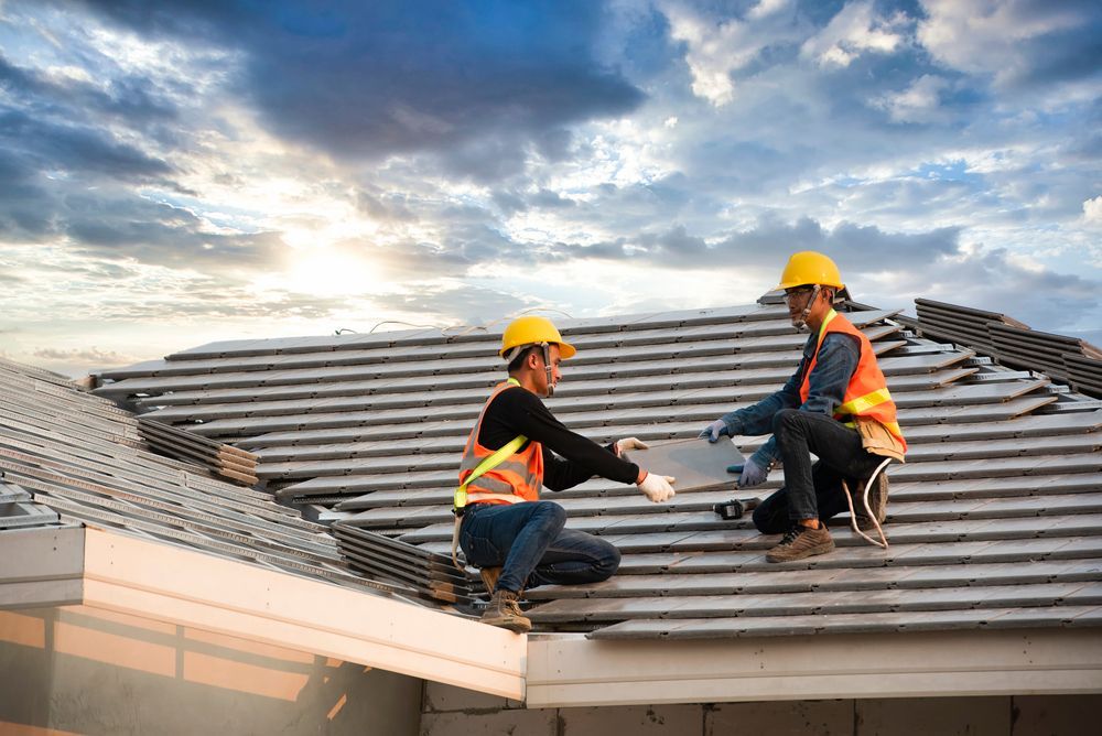 Two construction workers are working on the roof of a house.