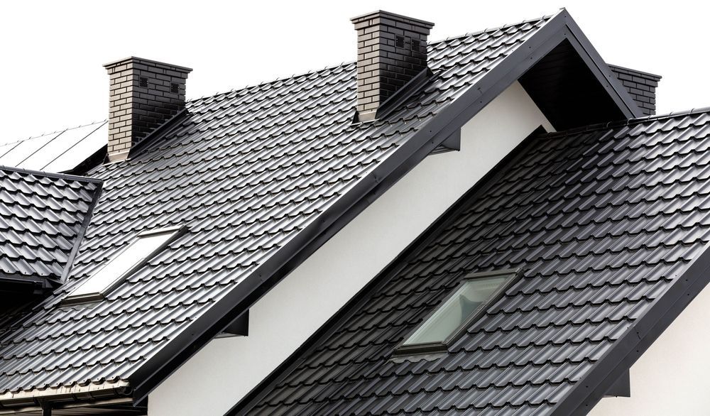 The roof of a house has a skylight and chimneys on it.