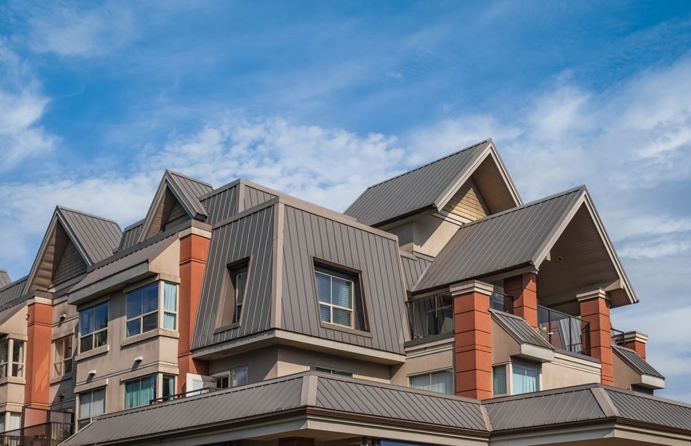 A large apartment building with a metal roof and chimneys.