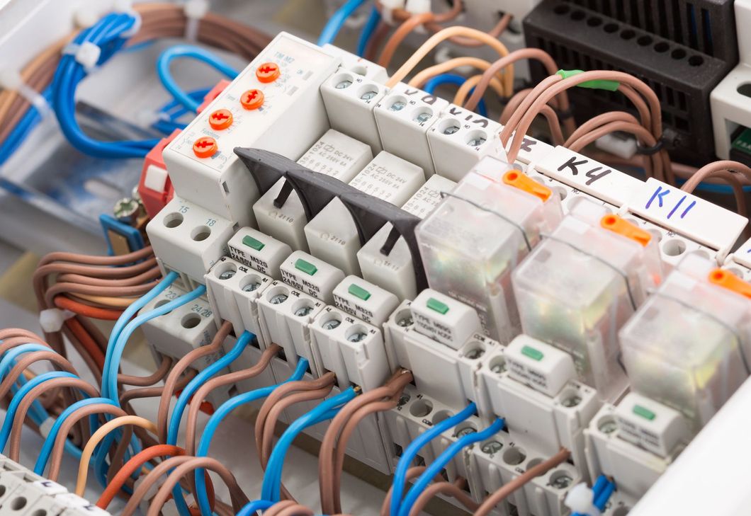 Vista ravvicinata di un quadro elettrico di controllo con numerosi fili collegati a relè e morsettiere.