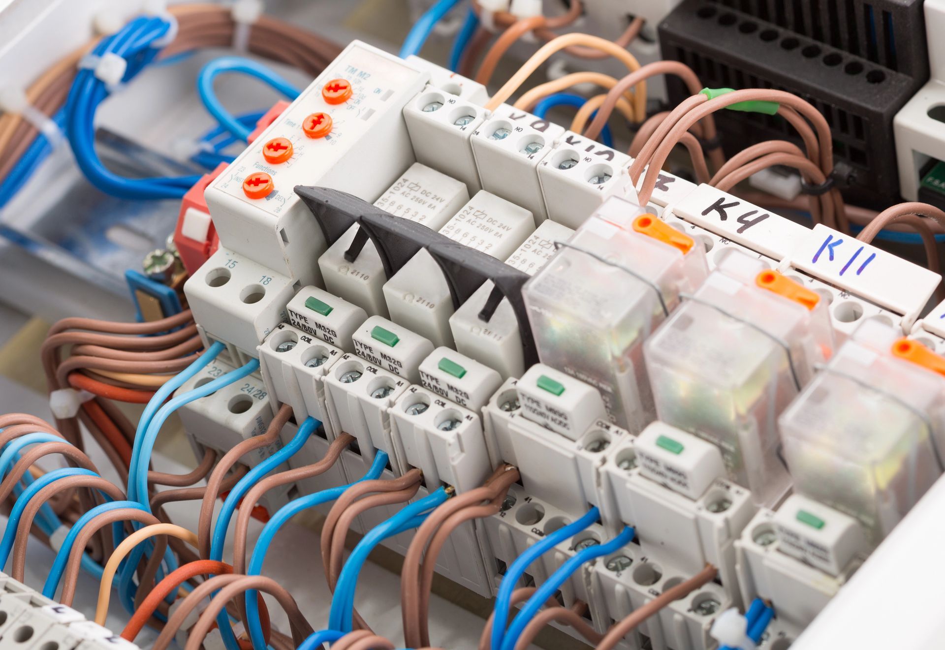 Vista ravvicinata di un quadro elettrico di controllo con numerosi fili collegati a relè e morsettiere.