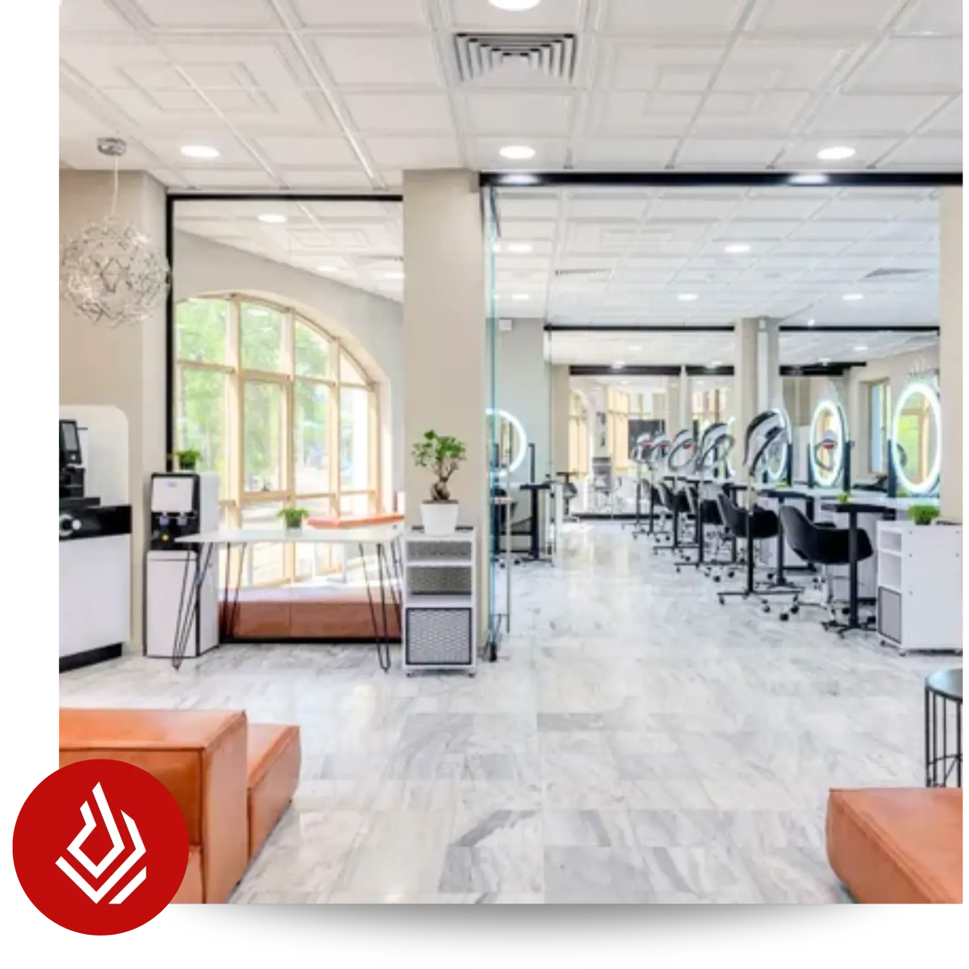 A brightly lit, modern salon or studio interior featuring a lounge area and a row of styling stations with circular lighted mirrors