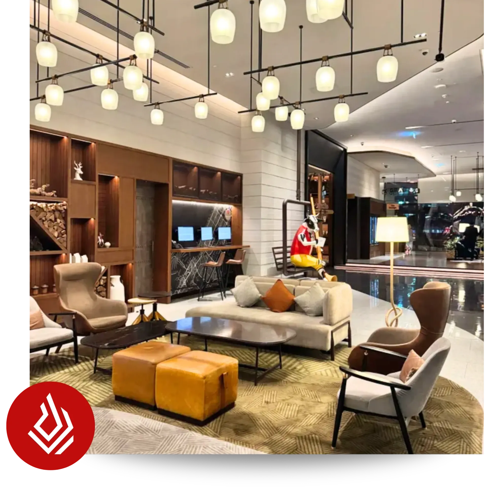 A modern hotel lobby featuring lounge seating areas and warm hanging pendant lights.
