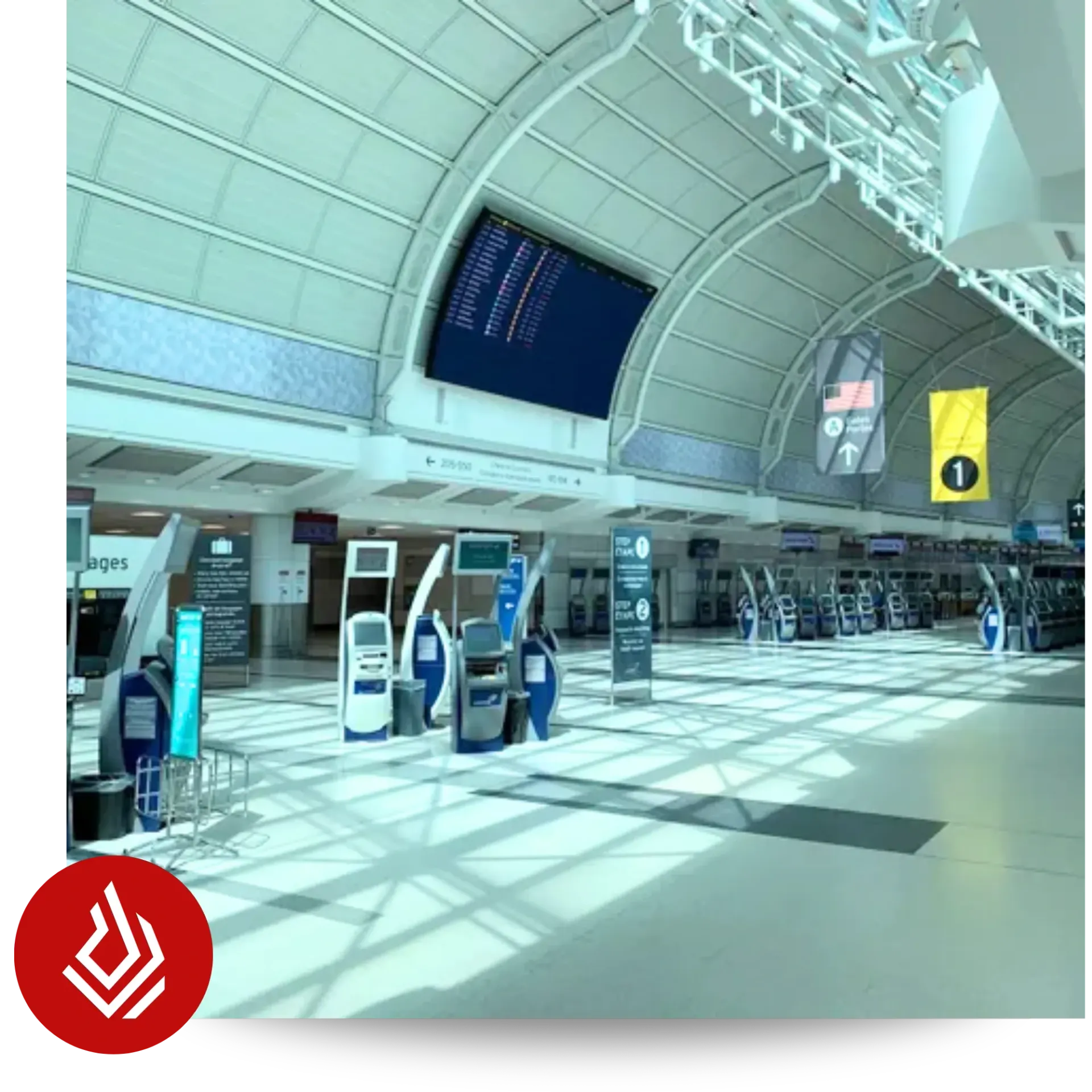 A spacious airport terminal featuring check-in kiosks and a large digital display beneath a high arched ceiling.