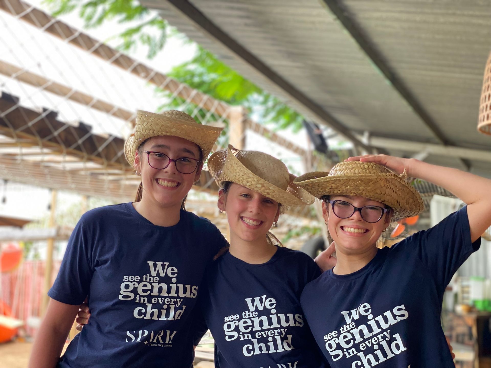 Three women wearing straw hats and glasses are posing for a picture.