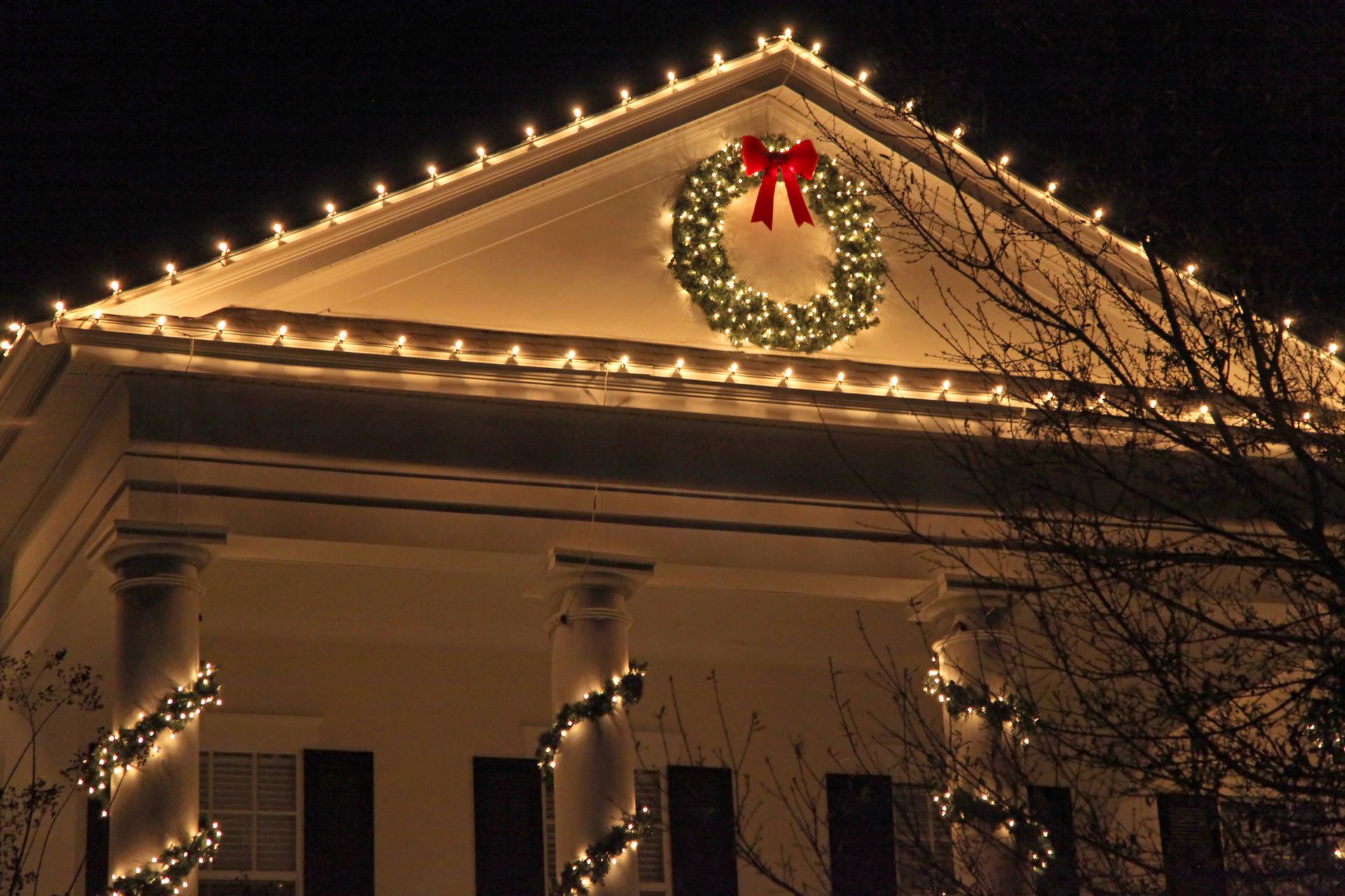 House decorated for Christmas with lights and a wreath on the roof.