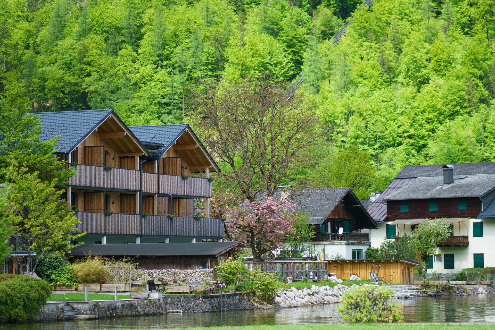 Lakeside wooden houses beside lush green trees and a calm waterway