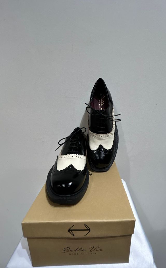 Persona che indossa stivali da lavoro in pelle marrone e pantaloni color cuoio in un negozio di scarpe.
