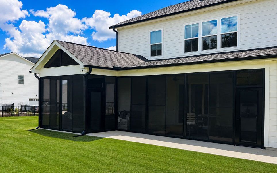 Backyard patio with screened enclosure attached to a two-story white house