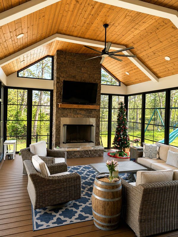 Cozy living room with stone fireplace, large windows, wicker furniture, and a decorated Christmas tree