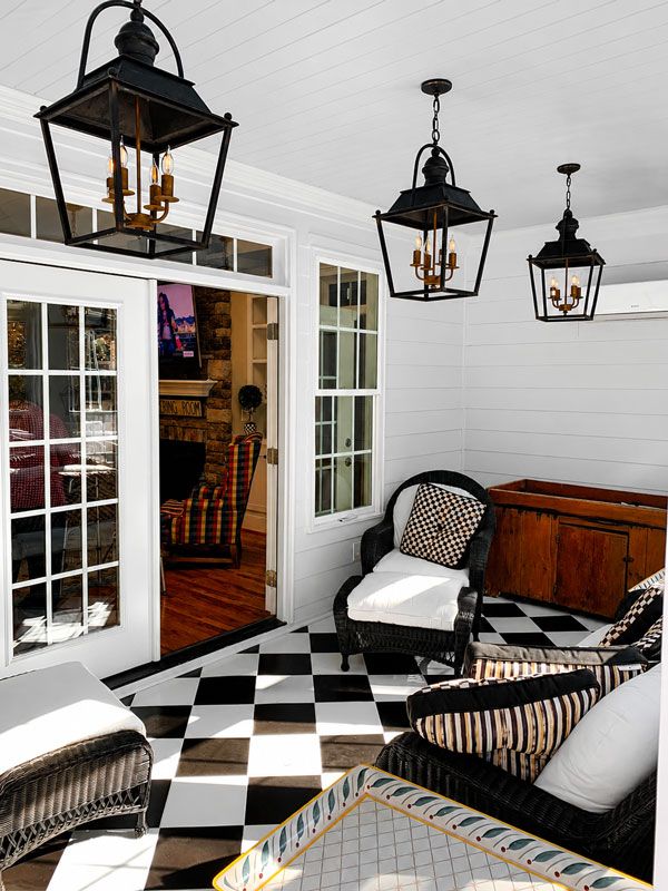 Black-and-white patio with hanging lanterns, open French doors, wicker chairs, and a wooden chest