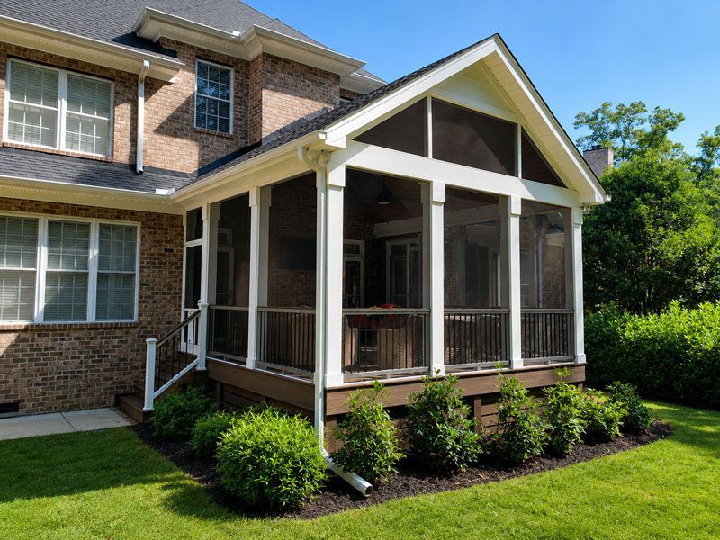 Screened porch on a brick house with white trim, steps, and green lawn