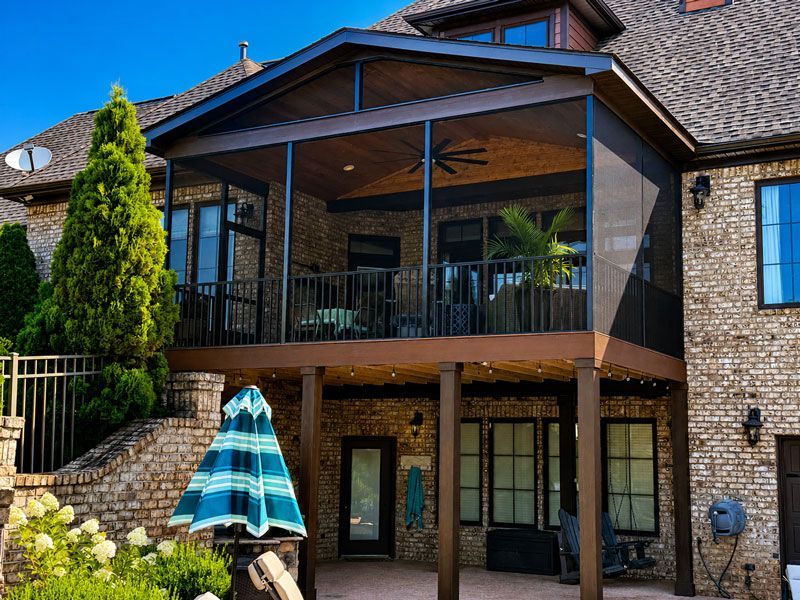 Two-story stone house with a covered screen room overlooking pool