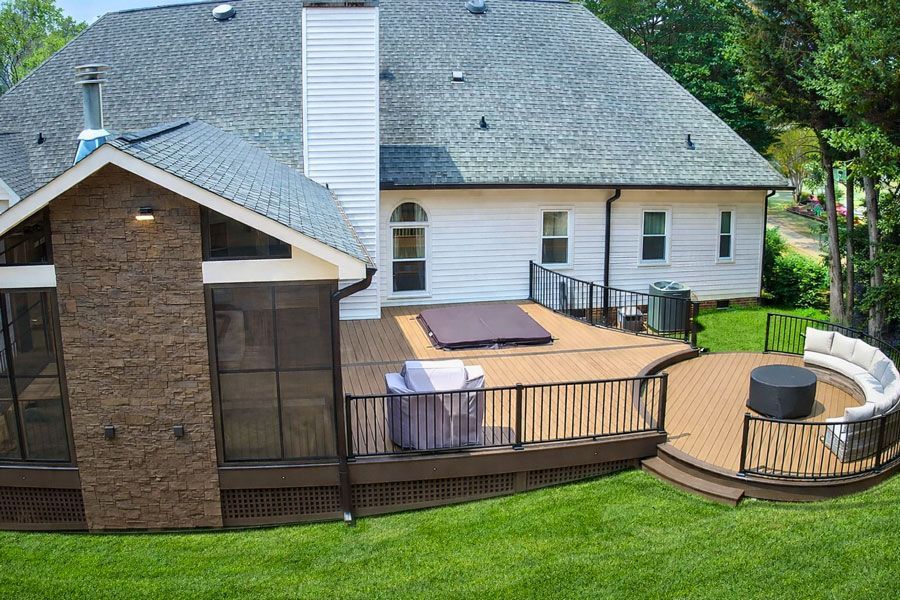 Custom backyard deck with wooden railing leading to a circular patio