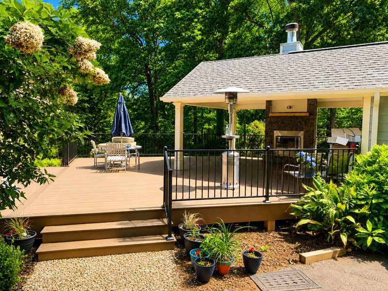 Backyard deck with covered patio, stairs, potted plants, and patio furniture