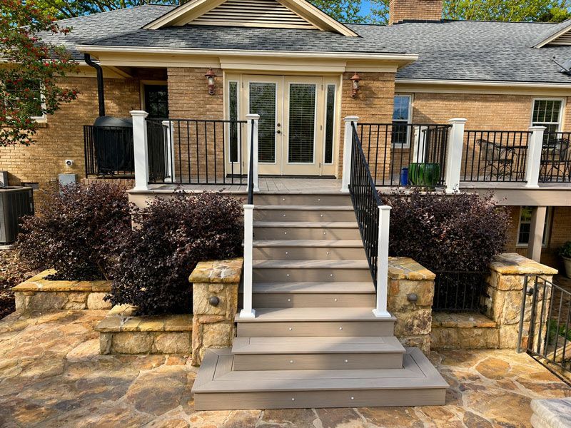 view of a brick house with a central staircase leading to glass double doors and a patio
