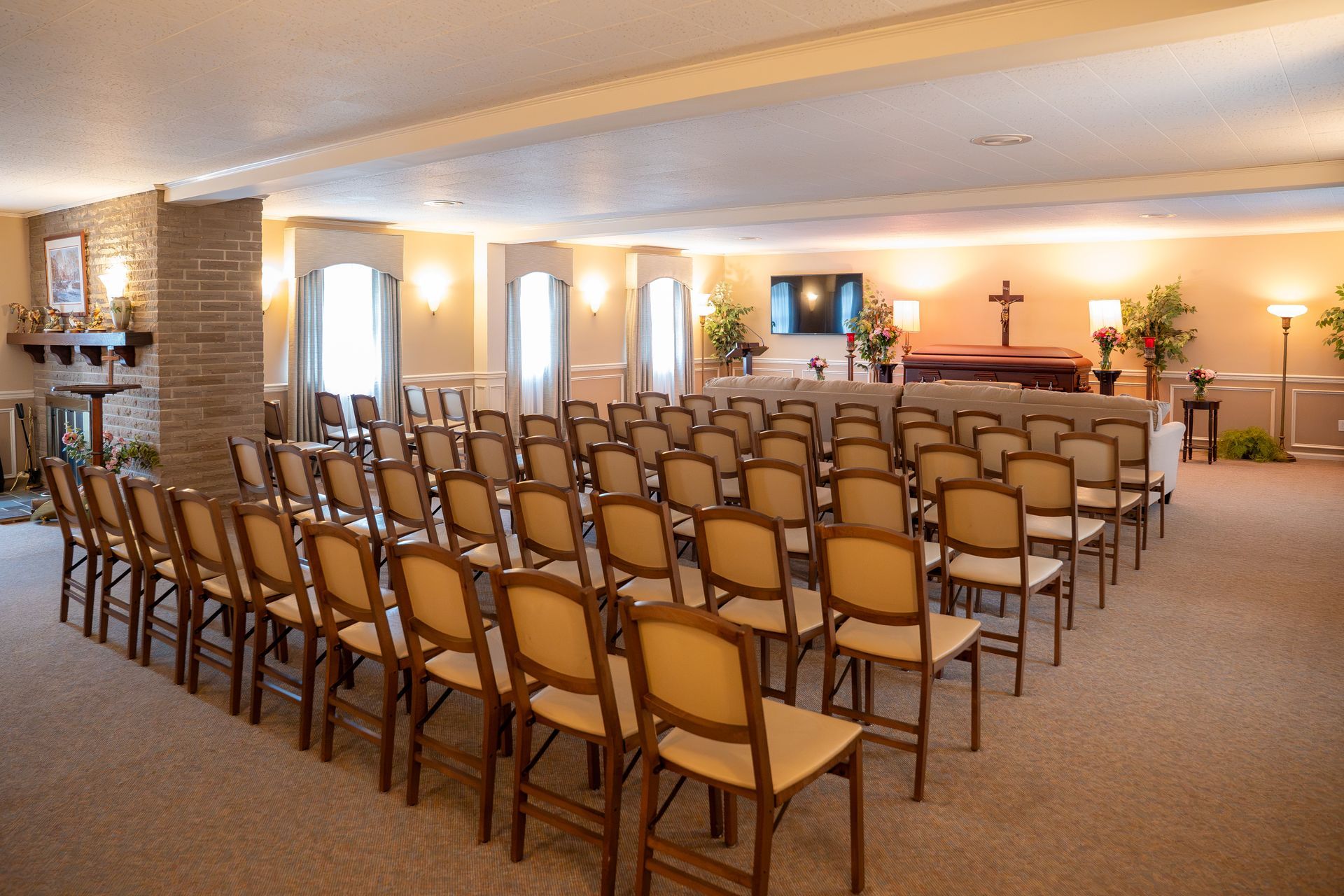 Empty chapel with rows of chairs facing a altar and cross under warm lighting
