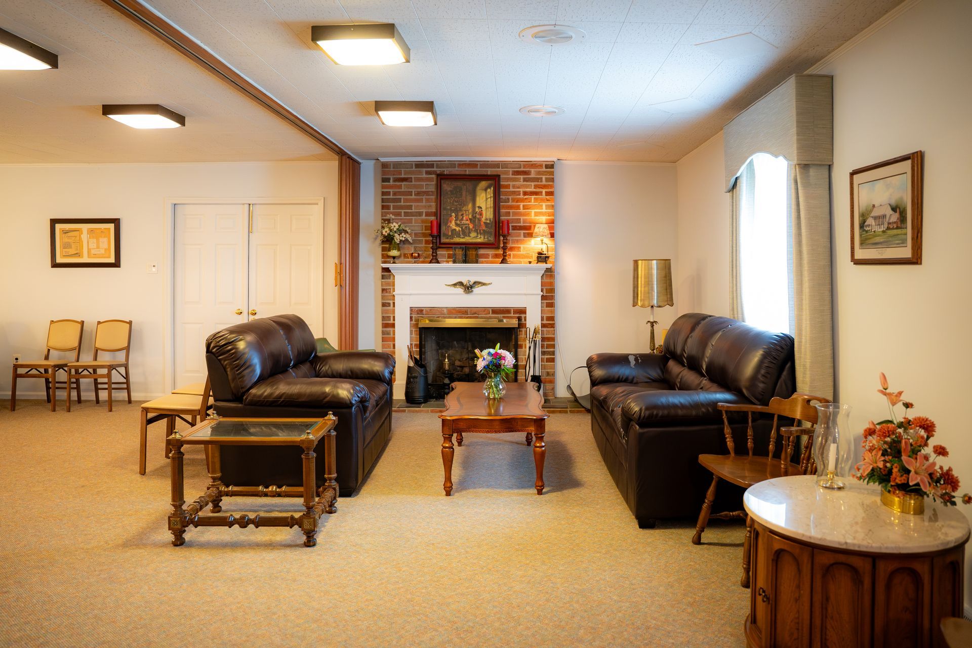 Living room with black leather sofas, fireplace, coffee table, and beige carpet