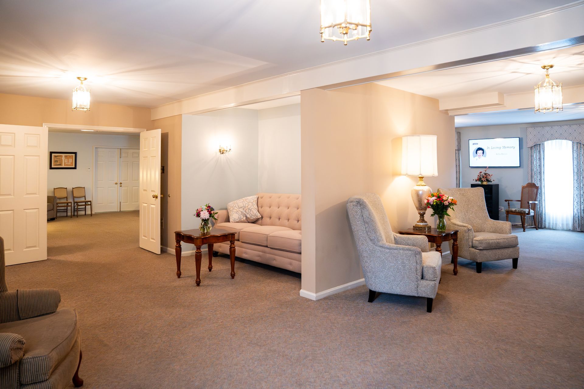 Elegant living room with beige walls, carpet, sofas, armchairs, and a small wooden table under pendant lights