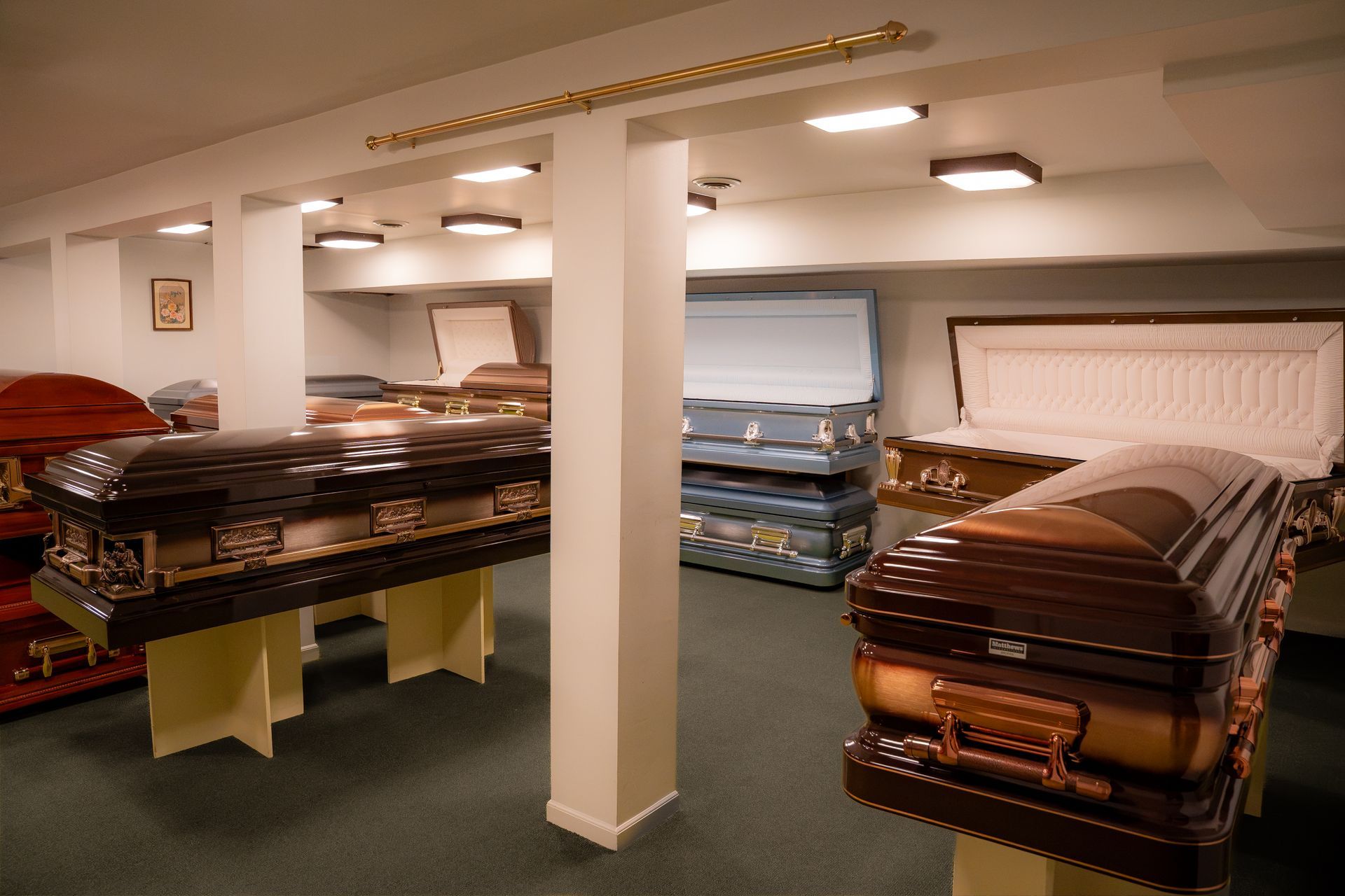 Showroom with two open caskets displayed on stands under warm lighting