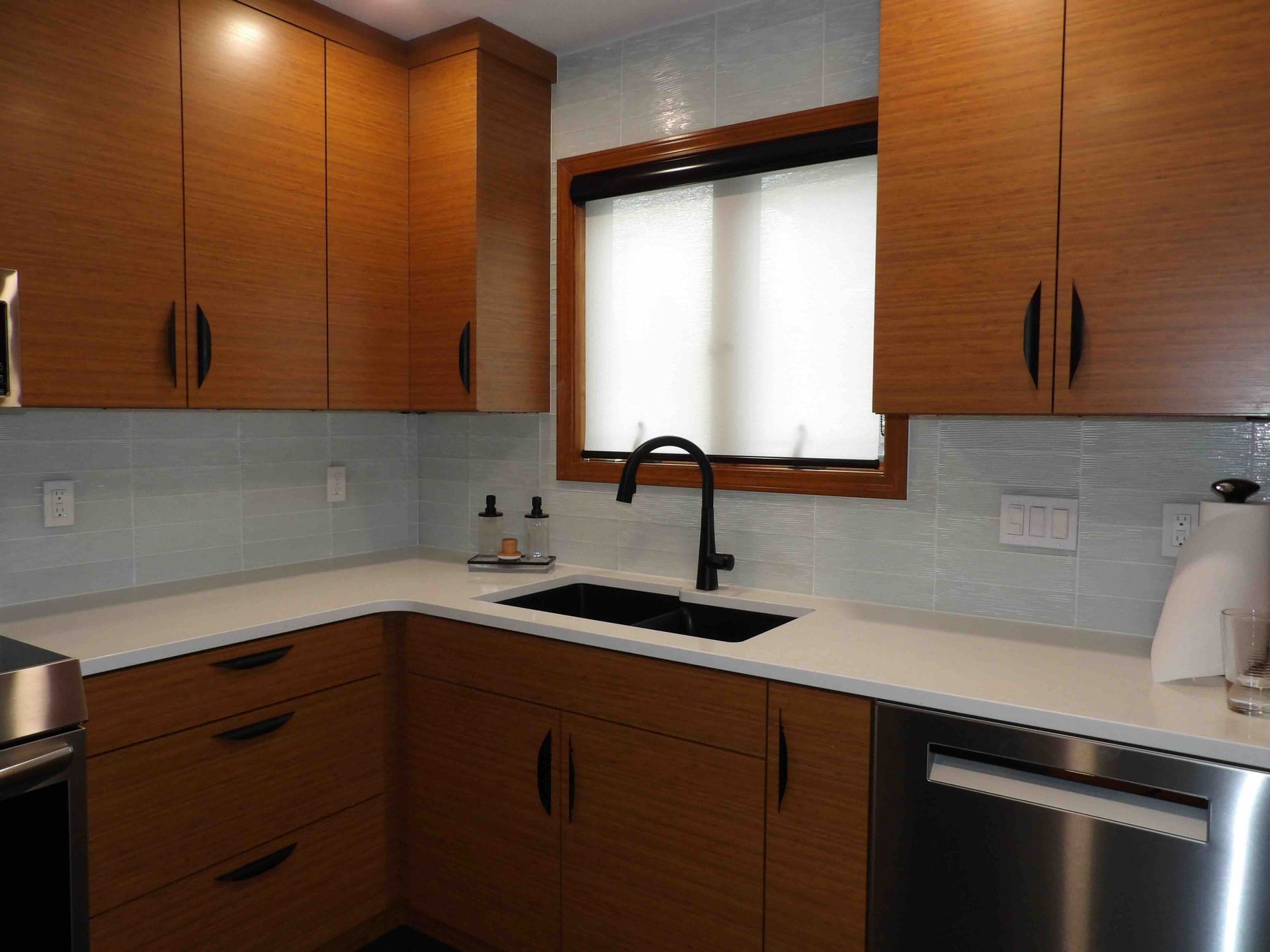 A kitchen with wooden cabinets , stainless steel appliances , a sink and a window.