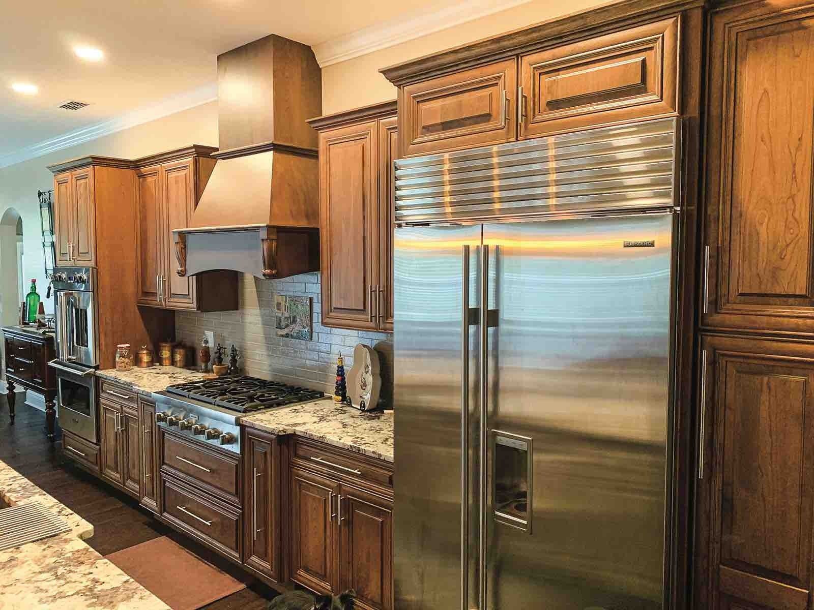 A black and silver hood is hanging from the ceiling in a kitchen.