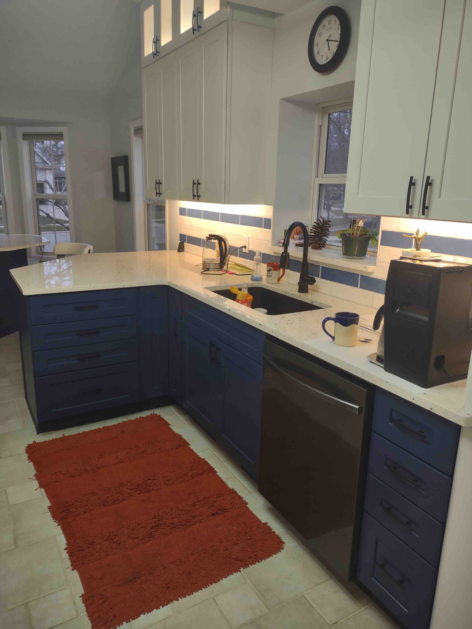 A kitchen with blue cabinets and a clock on the wall