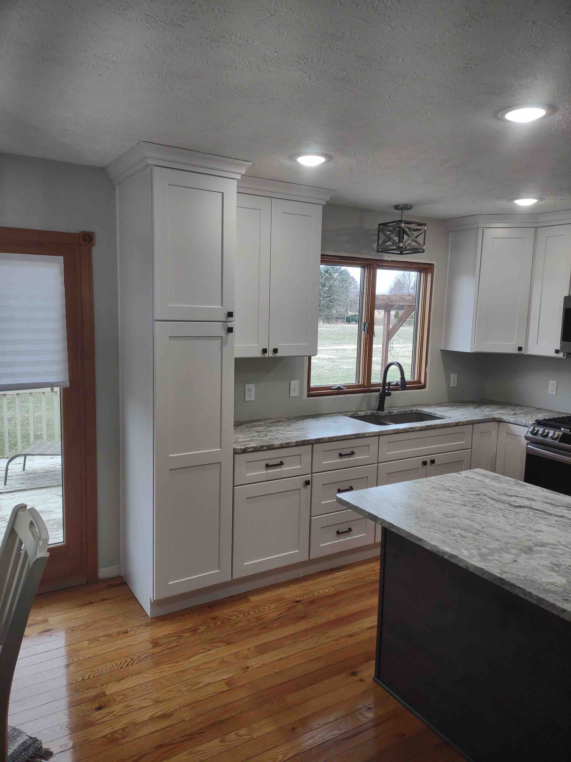 A kitchen with white cabinets and granite counter tops