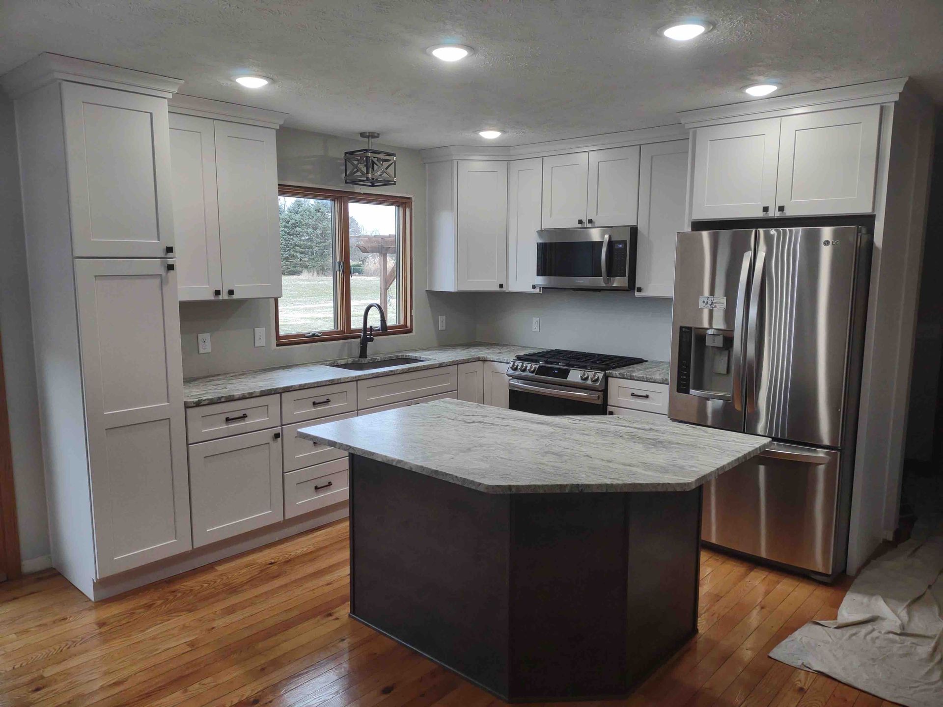 A kitchen with white cabinets , stainless steel appliances , and a large island.