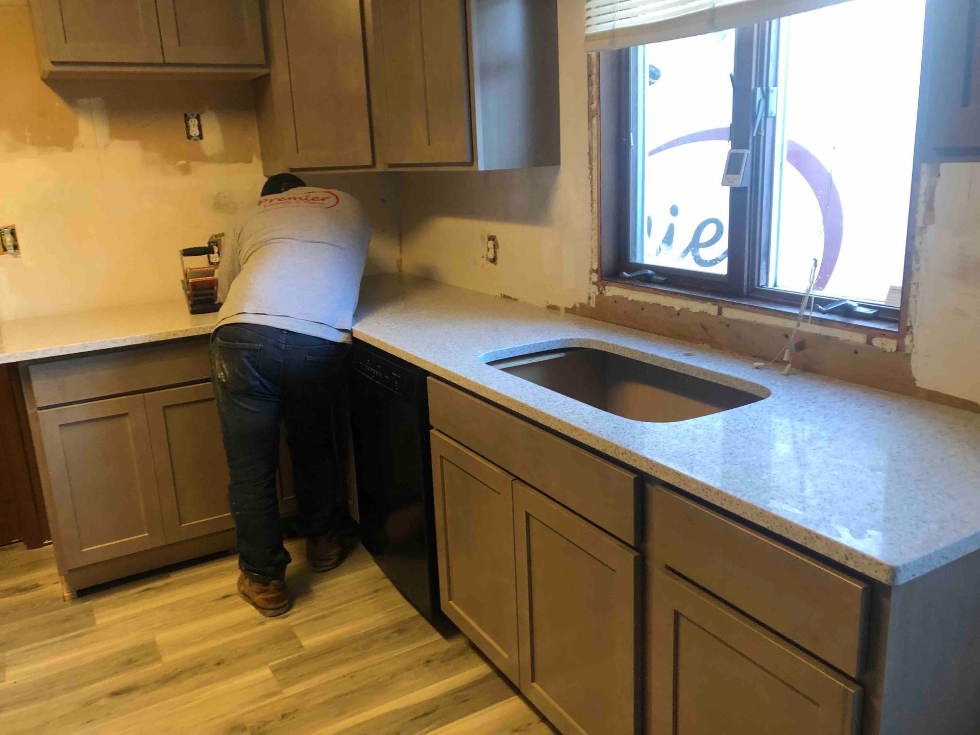 A man is working in a kitchen with a sink and cabinets.
