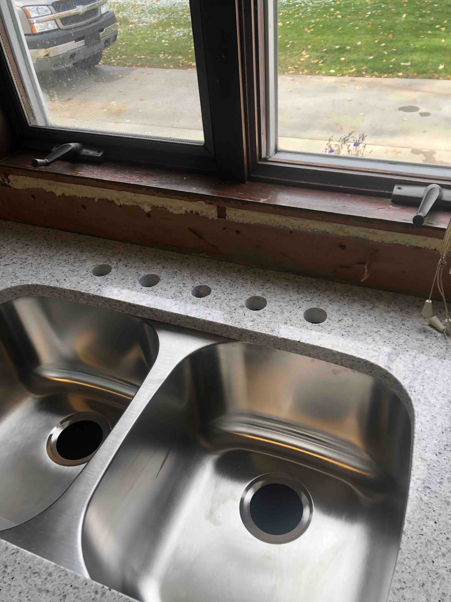 A stainless steel kitchen sink is sitting under a window.