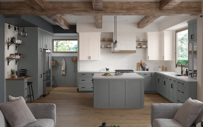 A kitchen with gray cabinets and white cabinets and a large island in the middle.
