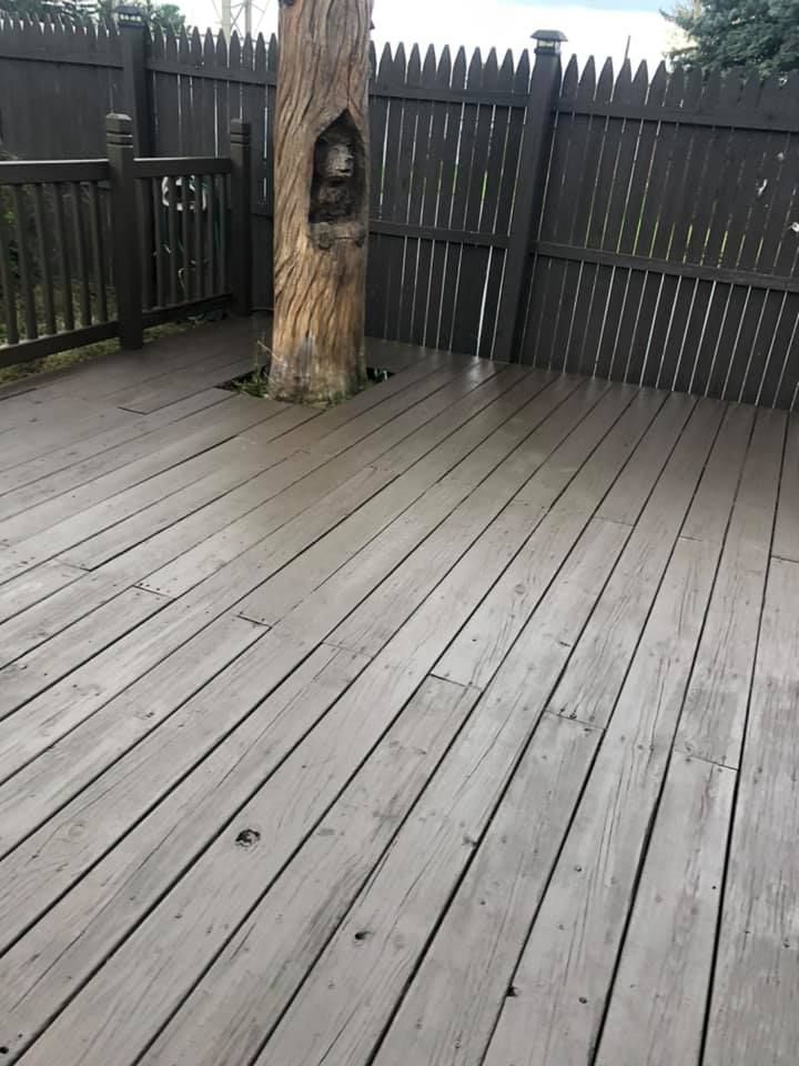 Wooden deck with black fence and a carved tree trunk in the center.