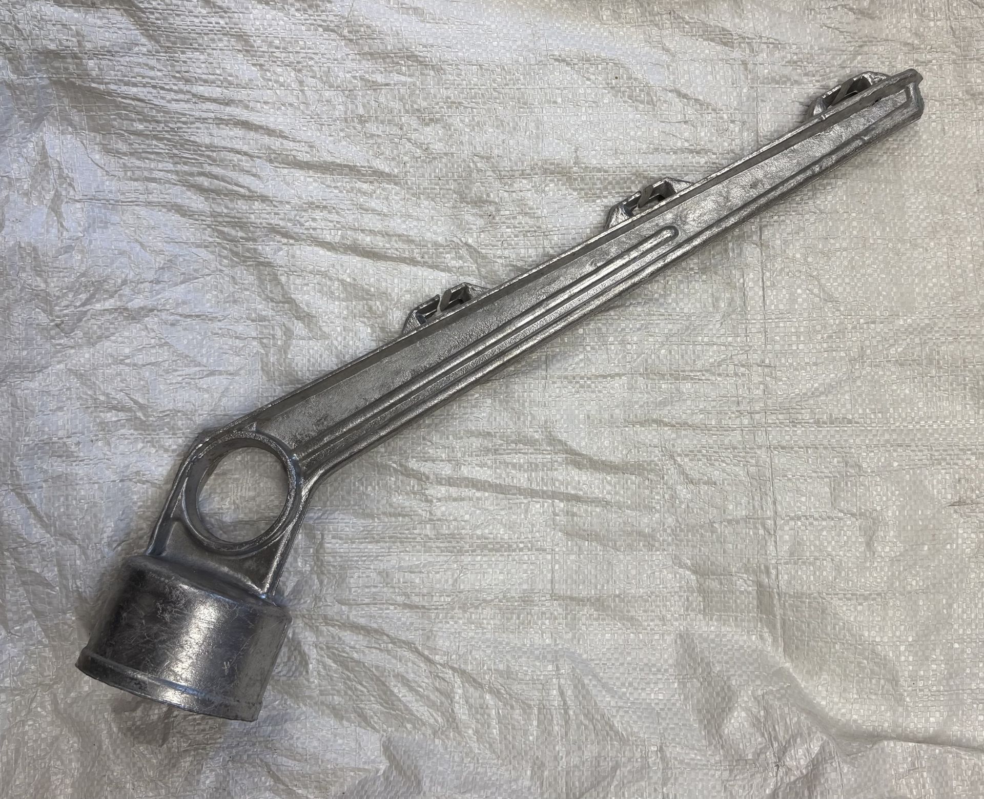 Clé métallique à base cylindrique et bras rainuré.