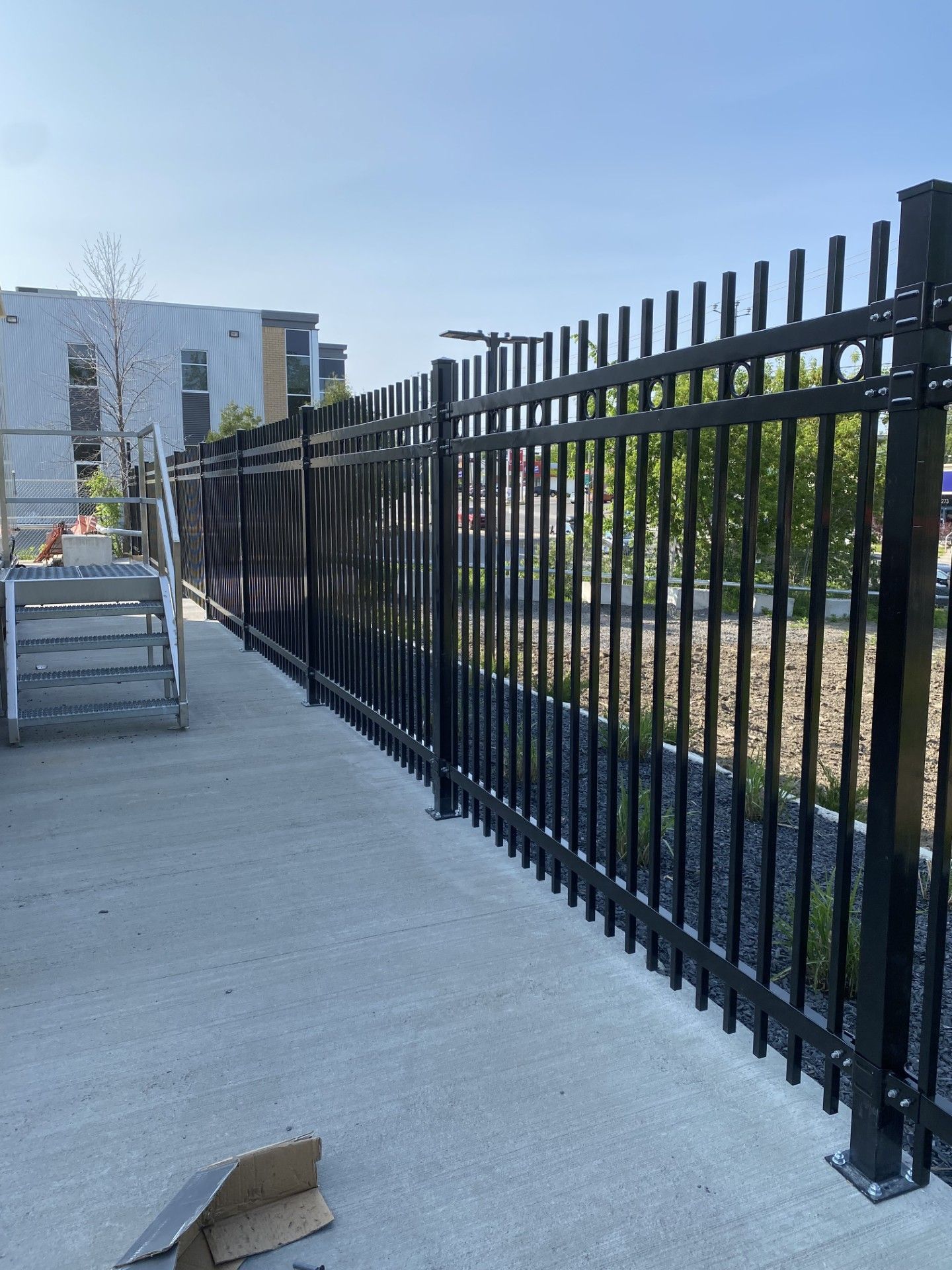Black metal fence along concrete walkway on a sunny day.