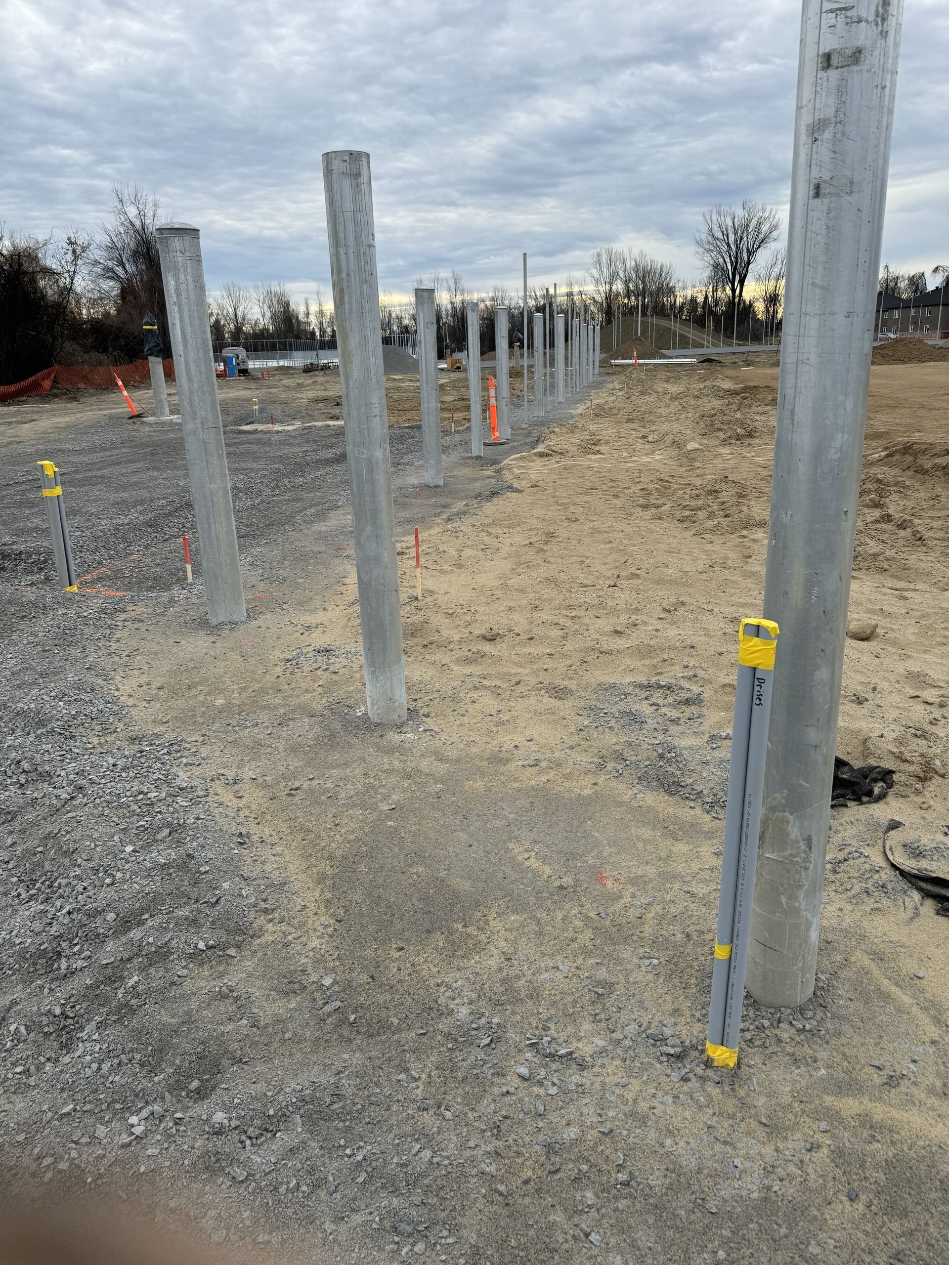 Concrete pillars under construction at a construction site on a gravel surface.