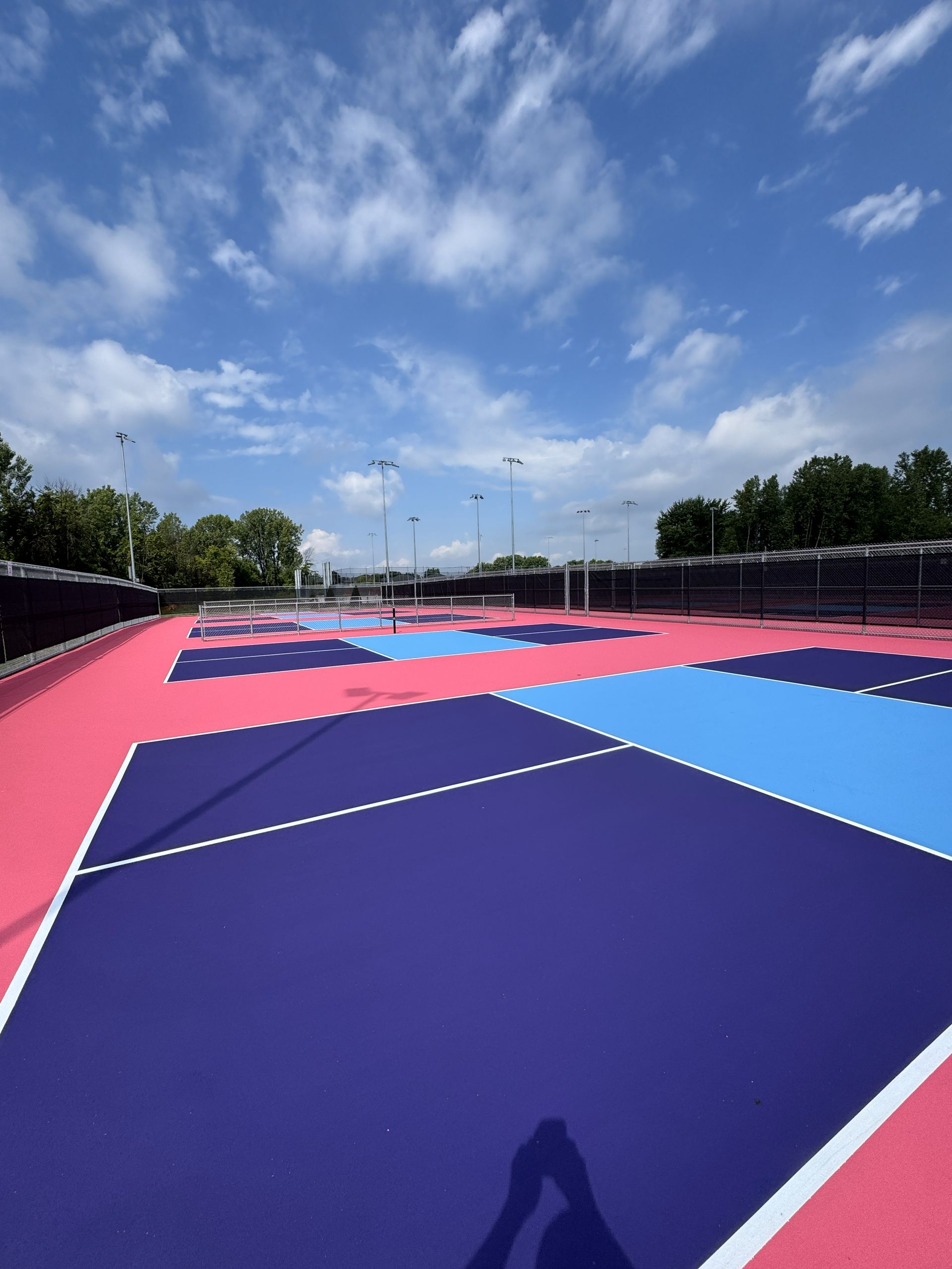 Colorful sports court, blue sky. Court painted pink, purple, and light blue.