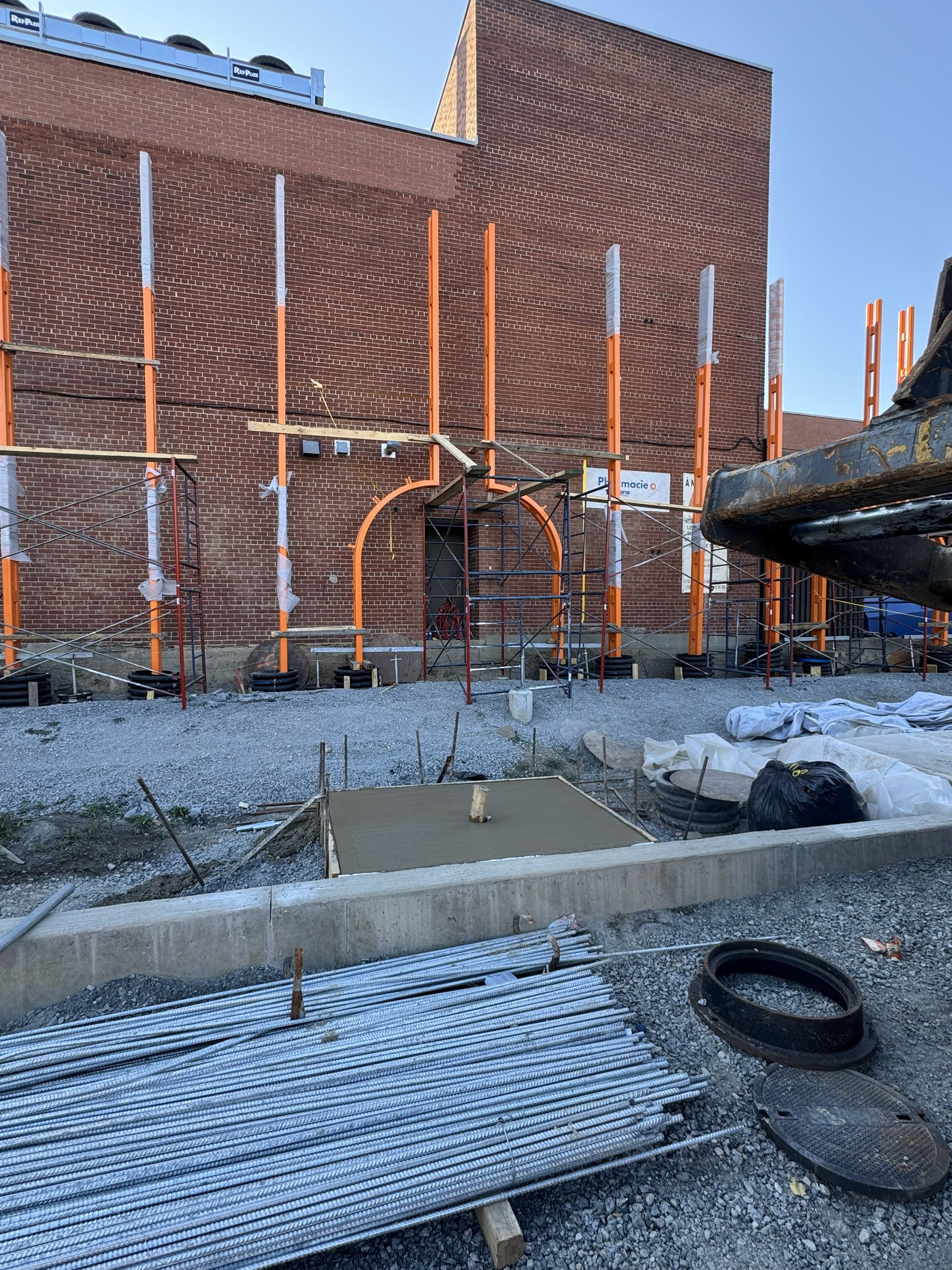 Construction site with brick building, scaffolding, and concrete work.
