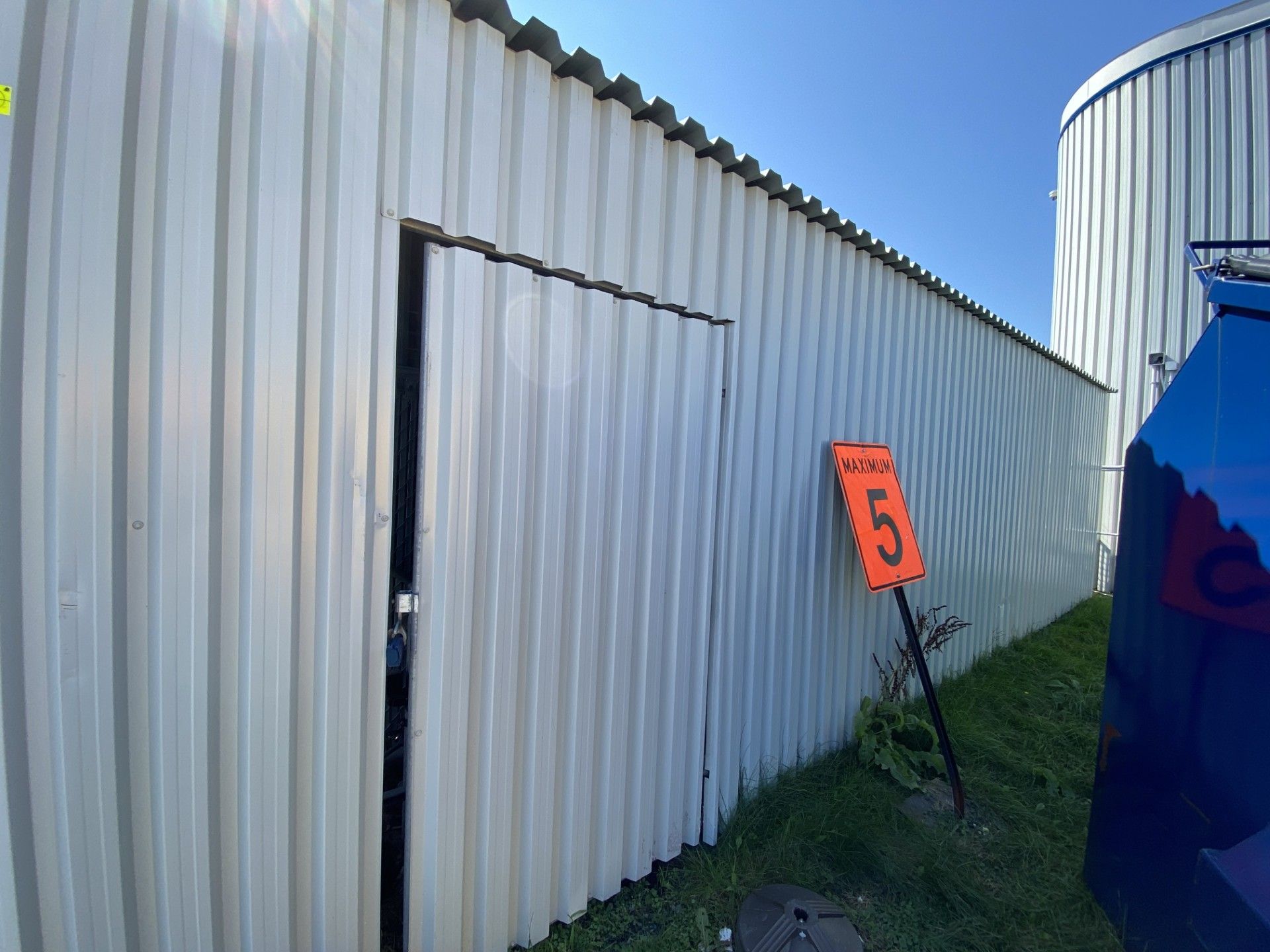 White corrugated metal building with a door and orange