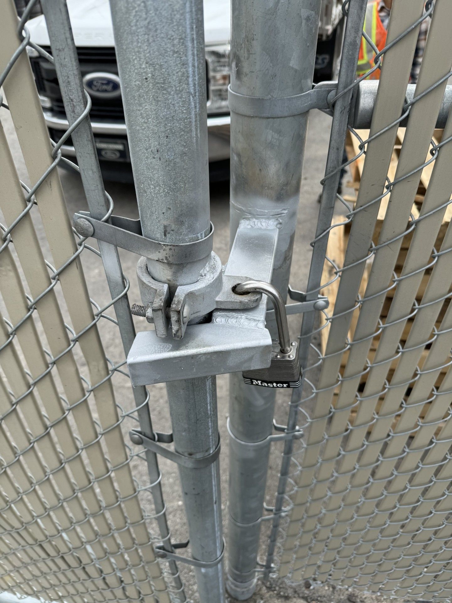 A chain-link fence gate is locked with a padlock, securing the enclosure.