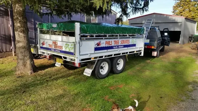 Two white utility trailers parked on grass under trees, one labeled “PAL SERVICE.” Two white utility trailers parked on grass under trees, one labeled “PAL SERVICE.”